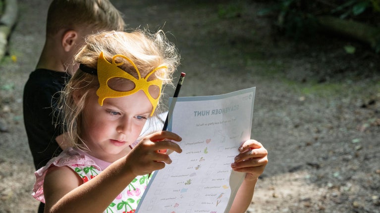 A young girl with pencil in hand looking intently at an activity trail sheet